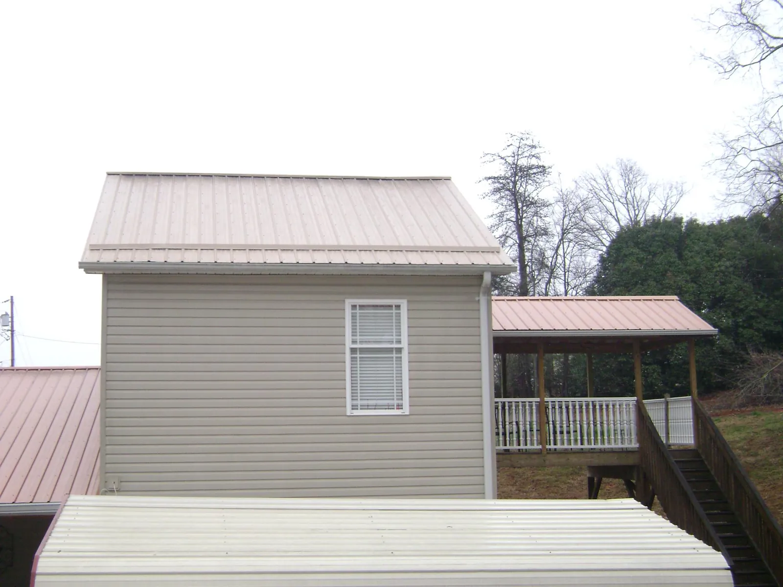 Tan metal roofs on a two story addition and attached porch, from a Roof Replacement job in Duncan