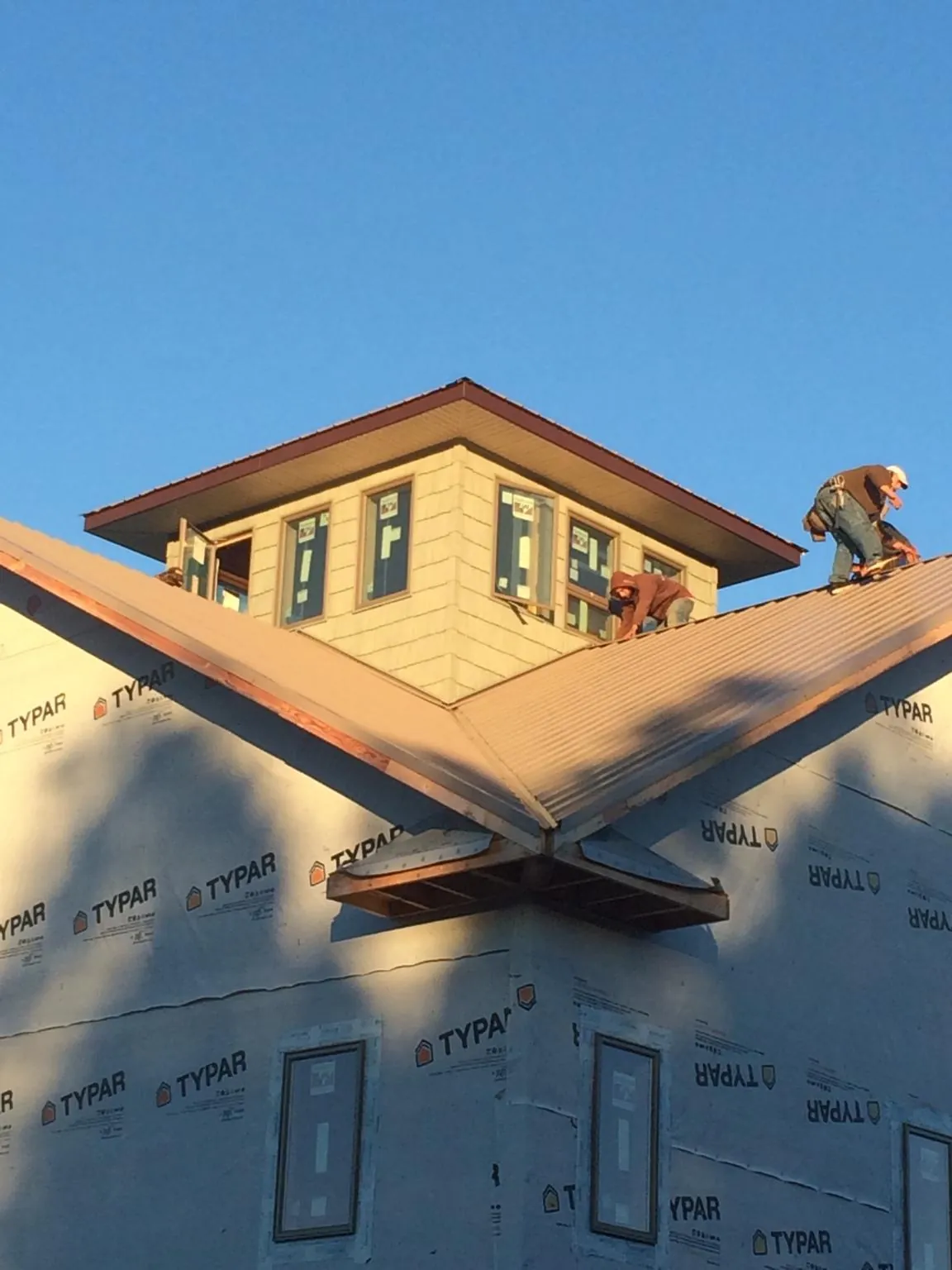 Roofers working around a rooftop cupola on a new metal roof at sunset — Roof Waterproofing in Duncan by Roofing Brothers